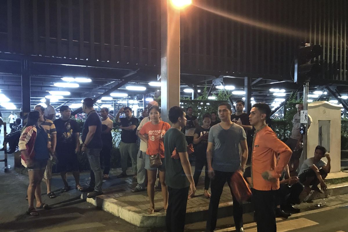 Employees and onlookers gather outside the Resorts World Manila complex, early Friday, June 2, 2017, in Manila, Philippines. Gunshots and explosions rang out early Friday at a mall, casino and hotel complex near Manila