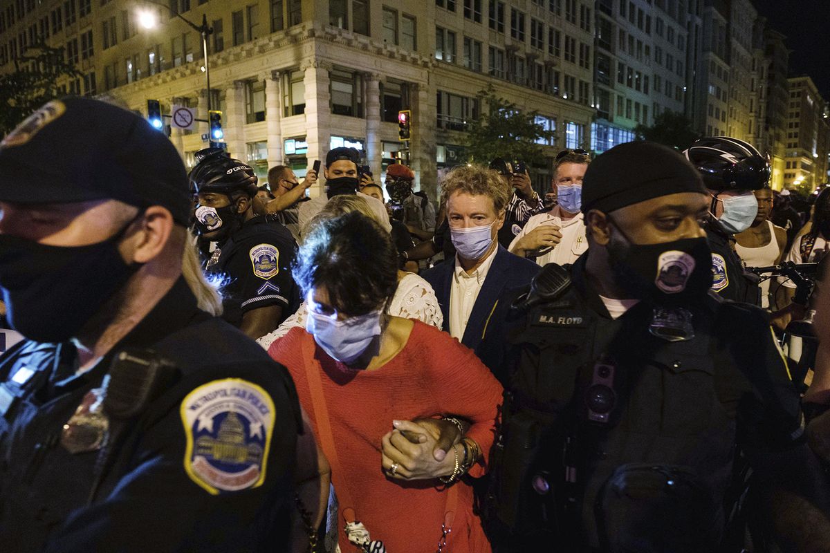 Sen. Rand Paul, R-Ky., center, and others, are escorted by Metropolitan Police after attending President Donald Trump