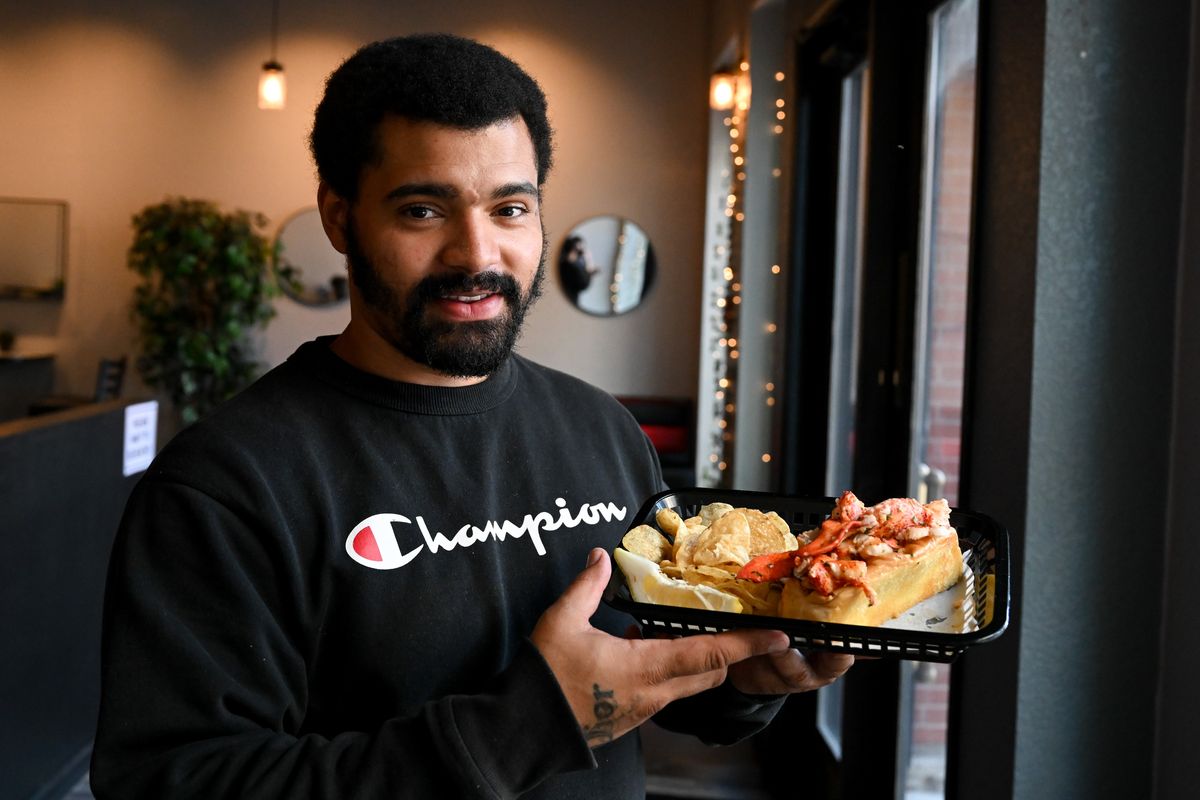 Makiel Duncan owner of Makiel’s Lobster Rolls poses for a photo with a Connecticut style lobster roll with extra meat and potato chips on July 19 at 115 N. Washington St. in Spokane. (Tyler Tjomsland/The Spokesman-Review)
