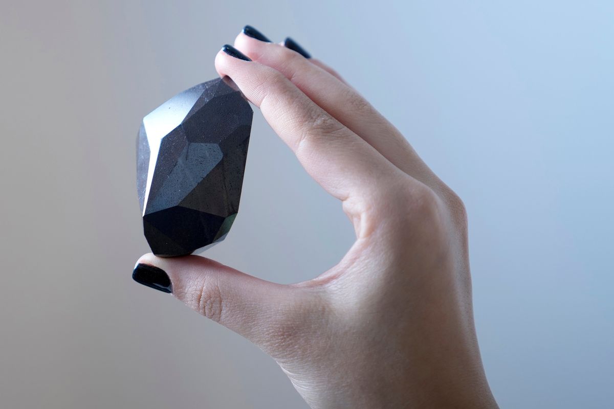 An employee of Sotheby’s Dubai presents a 555.55-carat black diamond, “The Enigma,” to be auctioned at Sotheby’s Dubai gallery, in Dubai, United Arab Emirates.  (Kamran Jebreili)