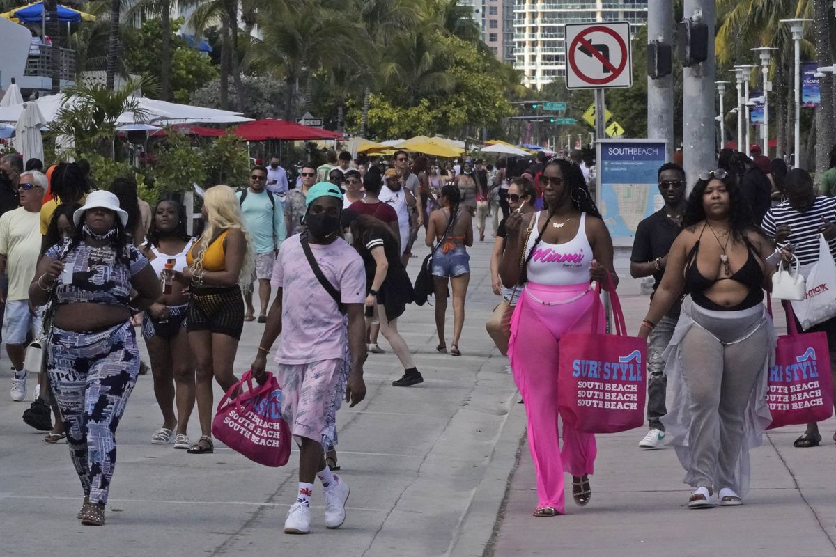 People in a mostly maskless crowd walk down Ocean Drive in Miami Beach, Florida