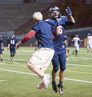 Mt. Spokane's Reed Siclair (cq) celebrates with assistant coach Kirk Clausen, left, after scoring a touchown against University High School on a long pass play Friday, Oct. 18, 2013 at Joe Albi Stadium.  The Wildcats beat the Titans handily 42-10. (Jesse Tinsley / The Spokesman-Review)