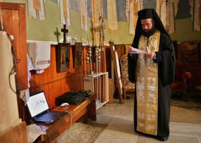 
Greek Orthodox priest Andreas Elime prays near a laptop computer in the Basilica of the Annunciation in the northern Israel town of Nazareth. Christian pilgrims long have traveled to the boyhood town of Jesus to seek blessings. Now the Internet can save them the trip.
 (Associated Press / The Spokesman-Review)