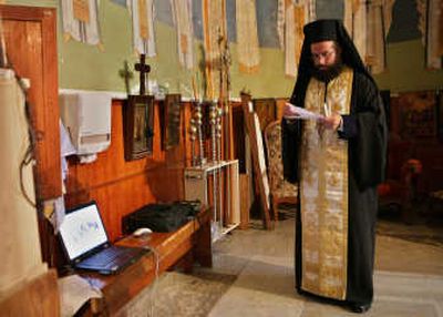 Greek Orthodox priest Andreas Elime prays near a laptop computer in the Basilica of the Annunciation in the northern Israel town of Nazareth. Christian pilgrims long have traveled to the boyhood town of Jesus to seek blessings. Now the Internet can save them the trip.
(Associated Press / The Spokesman-Review)