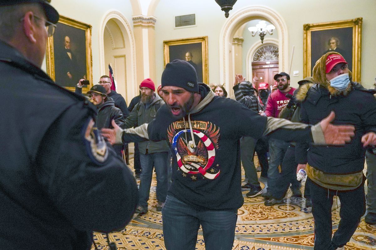 FILE - In this Jan. 6, 2021, file photo, Trump supporters, including Doug Jensen, center, confront U.S. Capitol Police in the hallway outside of the Senate chamber at the Capitol in Washington. A federal judge on Thursday, Sept. 2, 2021, ordered Jensen, a prominent participant in the Jan. 6 attack on the U.S. Capitol to return to jail after he was caught accessing the Internet to watch false conspiracy theories about the presidential election.  (Manuel Balce Ceneta)