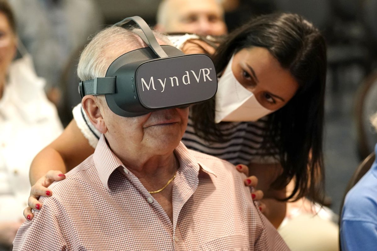 Gloria Gantes, right, monitors Terry Colli, a resident of John Knox Village, as he participates in a virtual reality study, Tuesday, June 1, 2021, in Pompano Beach, Fla. The senior community is in partnership with Stanford University