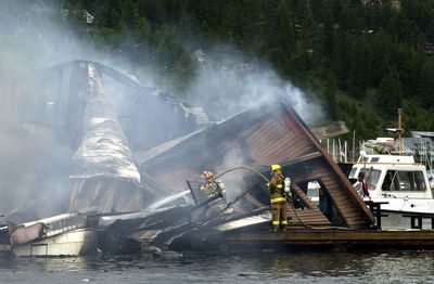 Firefighters use a hose  extinguish a fire at a float home in Bayview on Lake Pend Oreille in June 2001.  (File / The Spokesman-Review)