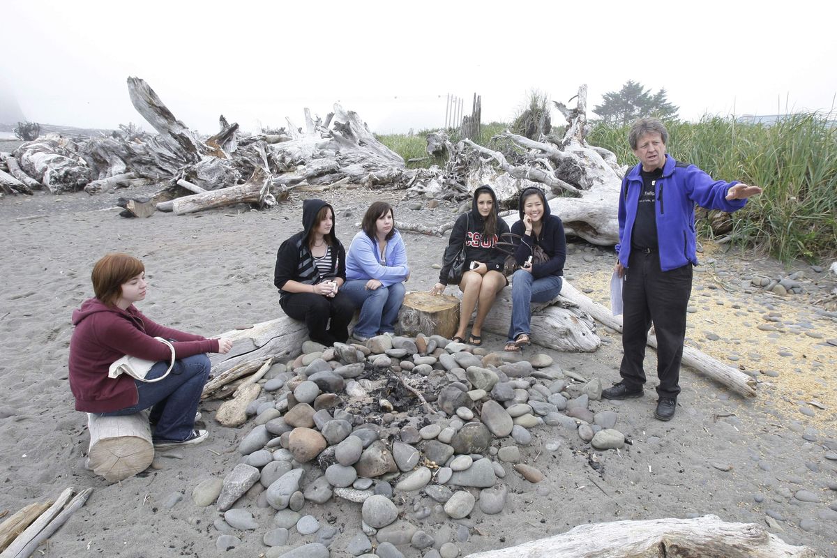 Visitors listen to Michael Gurling, right, of the Forks, Wash., Chamber of Commerce, talk about the bonfire location on a beach in LaPush, Wash., that is portrayed as the place where Bella Swan, the main character in the vampire-themed “Twilight” books, learns that her high-school friend Edward Cullen is really a vampire. The visitors were taking part in a “Twilight Tour” in 2008.  (Associated Press)