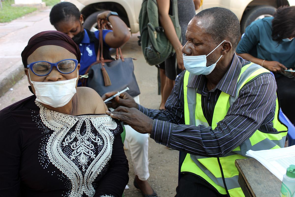 FILE - A woman receives a coronavirus vaccine in Abuja, Nigeria, Monday, Nov 29, 2021. A pandemic-weary world faces weeks of confusing uncertainty as countries restrict travel and take other steps to halt the newest potentially risky coronavirus mutant before anyone knows just how dangerous omicron really is.  (Gbemiga Olamikan)