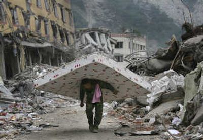 
A man carries a mattress in earthquake-battered Yingxiu, Sichuan Province, on Tuesday. Associated Press
 (Associated Press / The Spokesman-Review)