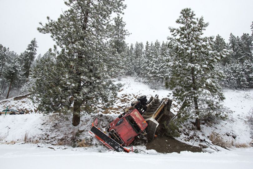 A Kootenai County Groomer Program truck slumps over the edge of East Fernan Lake Road Wednesday after the driver maneuvered to avoid colliding with an oncoming van. Icy conditions made recovery of the vehicle difficult for tow trucks, causing an extended delays for drivers along East Fernan Lake Road. (Gabe Green/press)