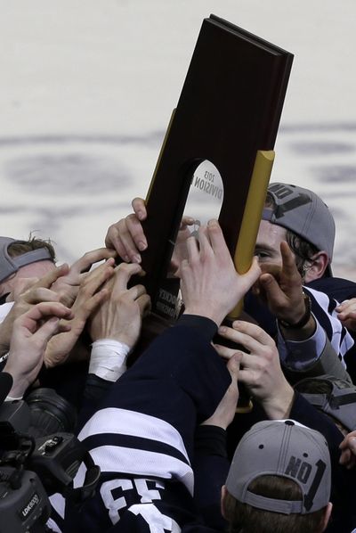Members of the Yale men’s hockey team hoist the trophy for winning the NCAA college hockey Frozen Four national title. (Associated Press)