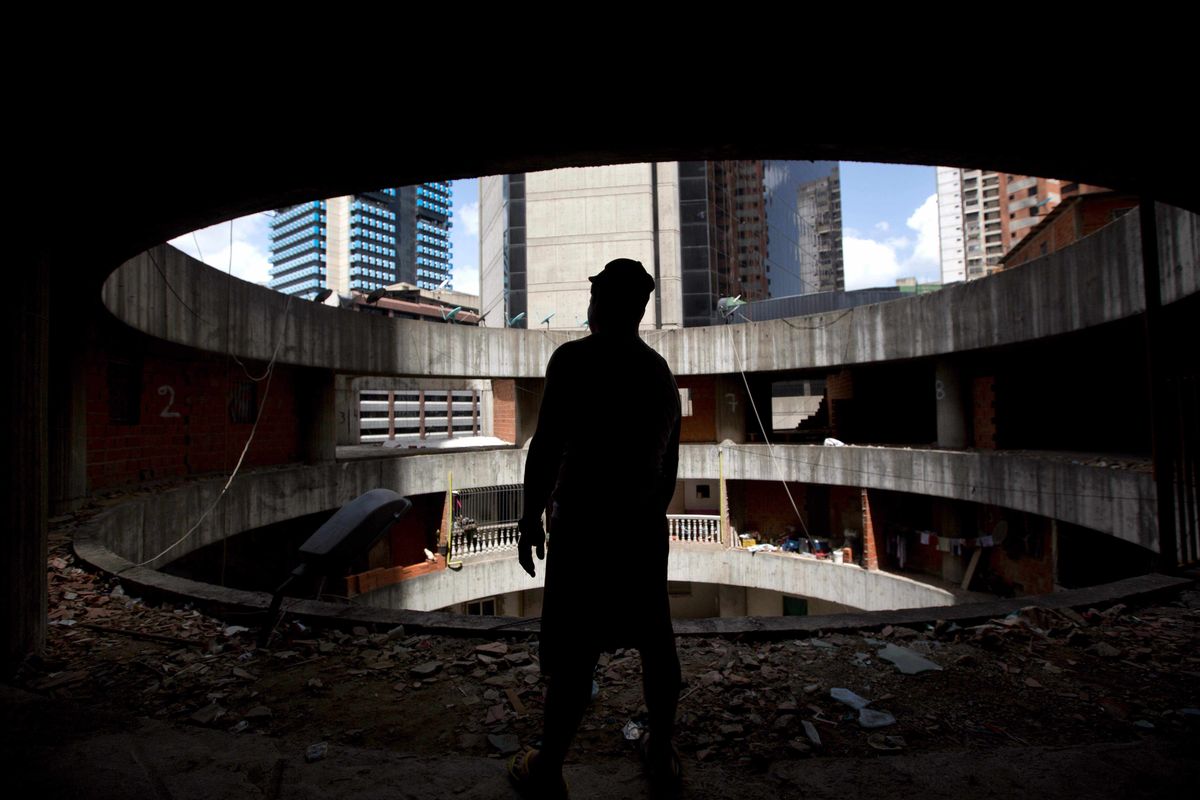 A resident waits for transportation to a new home after being evicted from an abandoned skyscraper in Caracas, Venezuela. On Tuesday, soldiers began moving out the thousands of squatters who have lived there nearly a decade. (Associated Press)