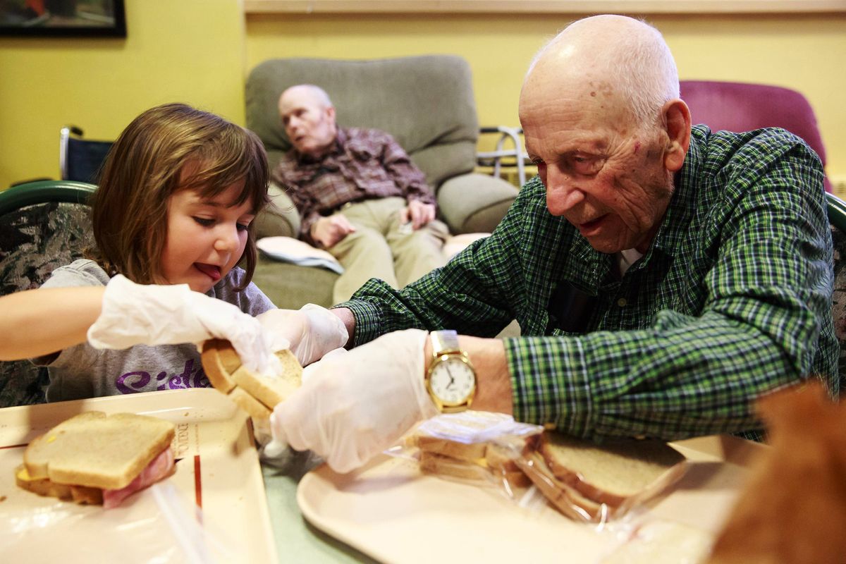 Alex Stafie, 5, and Wallace Scherer, 92, make sack lunches for the homeless during an activity at Providence Mount St. Vincent home for older adults in West Seattle.