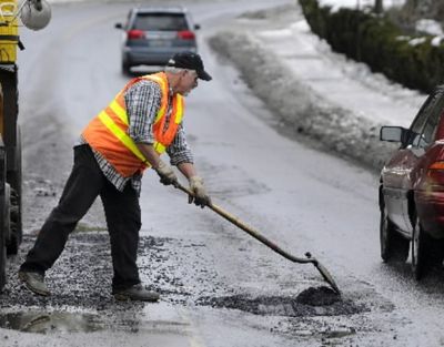 A Spokane city worker dumps one last shovel of cold mix into a pothole he classified as a 