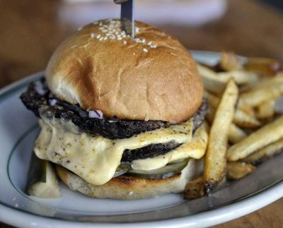 The single burger at Durkin’s Liquor Bar in downtown Spokane comes with two patties plus shaved pickles, American cheese and dill mayo - and it’s glorious. (Adriana Janovich / The Spokesman-Review)