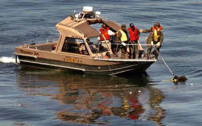 Military investigators collect a large piece of floating aircraft debris Thursday from Wednesday's midair crash of two F-18 jets near Arlington, Ore.
(Associated Press / The Spokesman-Review)