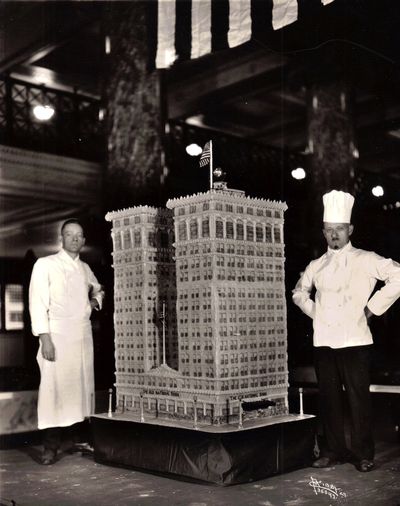 The article in the Spokane Daily Chronicle that accompanied this photo explained that the Money Cake weighed 1,100 pounds. It was designed and baked by chefs at the Davenport Hotel and was as tall as the chefs who made it.