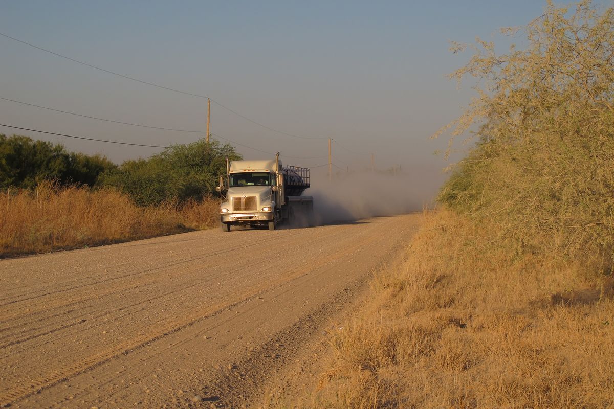 A truck travels along the stretch of gravel road near La Joya, Texas, Friday Oct. 26, 2012, where a Texas Department of Public Safety helicopter and sharpshooter assisted the previous day in the chase of a suspected illegal immigrant smuggler. Two people in the fleeing vehicle were killed and a third was wounded. (Chris Sherman / Associated Press)