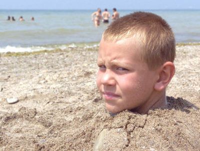 
Cody Stevenson, 7, is buried up to his neck in sand while trying to avoid the hot sun Monday at Walnut Beach in Ashtabula, Ohio. 
 (Associated Press / The Spokesman-Review)
