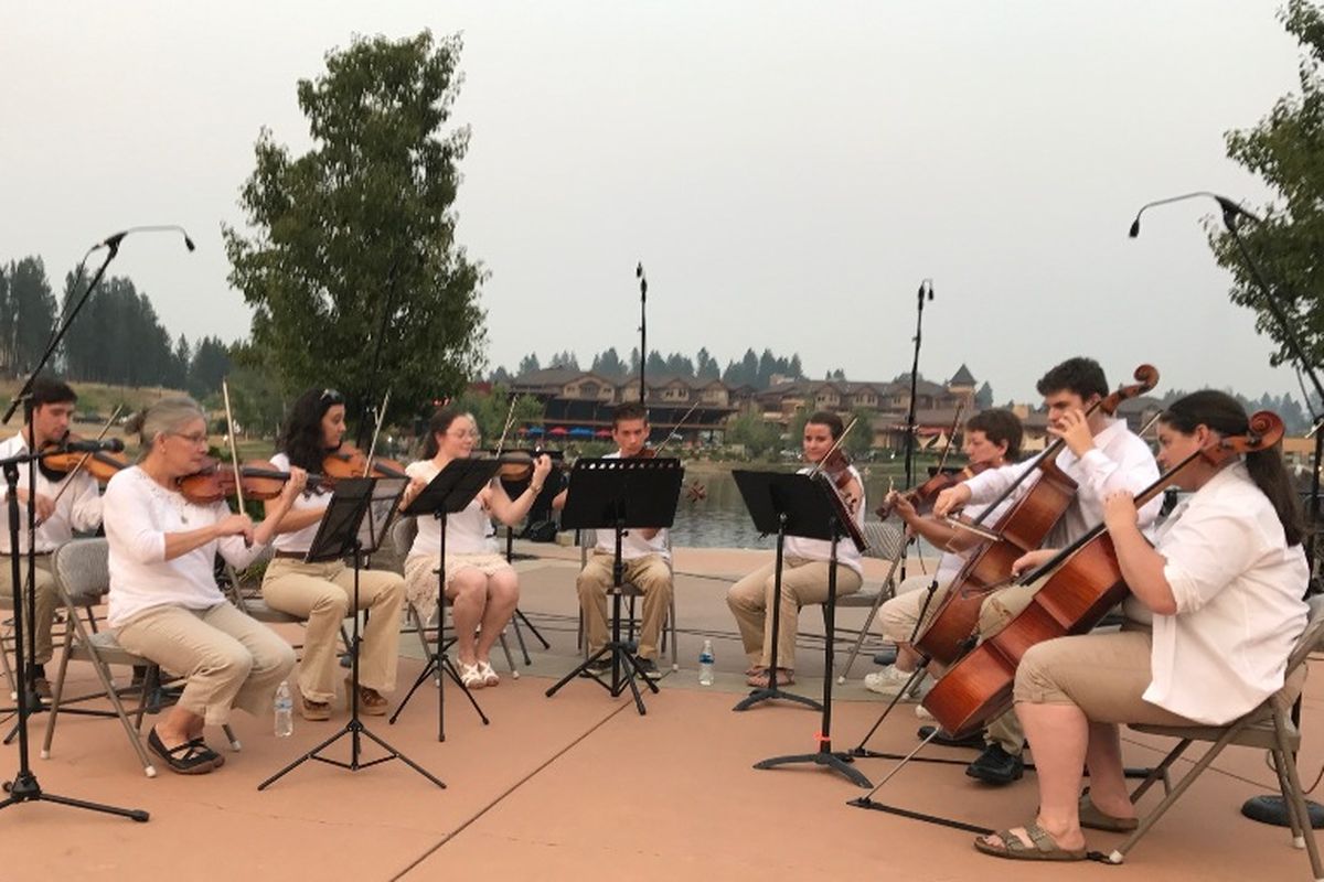 Cathyanne Nonini, left front, leads the strings section of the Coeur d'Alene Symphony during a performance at Riverstone Pond Thursday night, sponsored by the Coeur d'Alene Arts & Culture Alliance. (Duane Rasmussen photo)