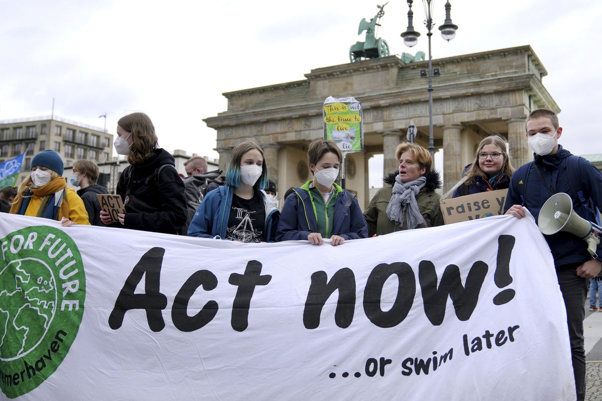 People stay in front of the Brandenburg Gate as they take part in a