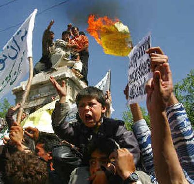 
Afghan students toss a burning paper with a drawing of U.S. President George W. Bush next to the words 