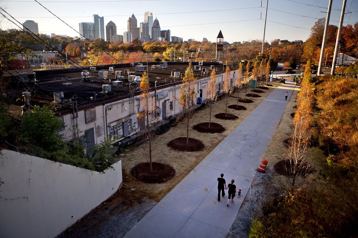 In this Nov. 20, 2012 photo, a couple walks along the Atlanta BeltLine as the midtown skyline stands in the background in Atlanta. Since an Atlanta nonprofit opened a 2.25-mile-long paved trail east of downtown last month, it has attracted a steady stream of joggers, dog-walkers and cyclists to take in spectacular views of the skyline as well as a slice of established neighborhoods that were once only seen by riding a freight train. The Eastside Trail is the latest and most visible phase of the Atlanta BeltLine, an ambitious $2.8 billion plan to transform a 22-mile railroad corridor that encircles Atlanta into a network of parks, trails, public art, affordable homes and ultimately streetcars. (David Goldman / Associated Press)