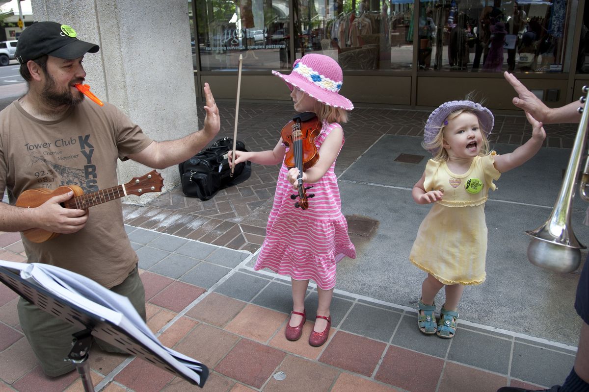 Carey Eyer, left, gives his daughter, Neilia, 5, a high five as Ivy, 3, gets another one after performing a song on Wall Street at Main Avenue during the 12th annual Street Music Week in downtown Spokane, the Garland District and downtown Coeur d’Alene. (Dan Pelle)