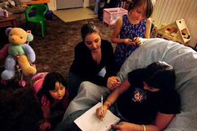 
Angee Friedrich helps her daughter, Karen, 11, with her sixth-grade language homework as her other daughters, Theresa, standing, and Marianne watch at their north Spokane home on Wednesday night. Friedrich, who earns less than $10 an hour, struggles to pay her monthly bills and put food on the table for her family. 
 (Jed Conklin / The Spokesman-Review)