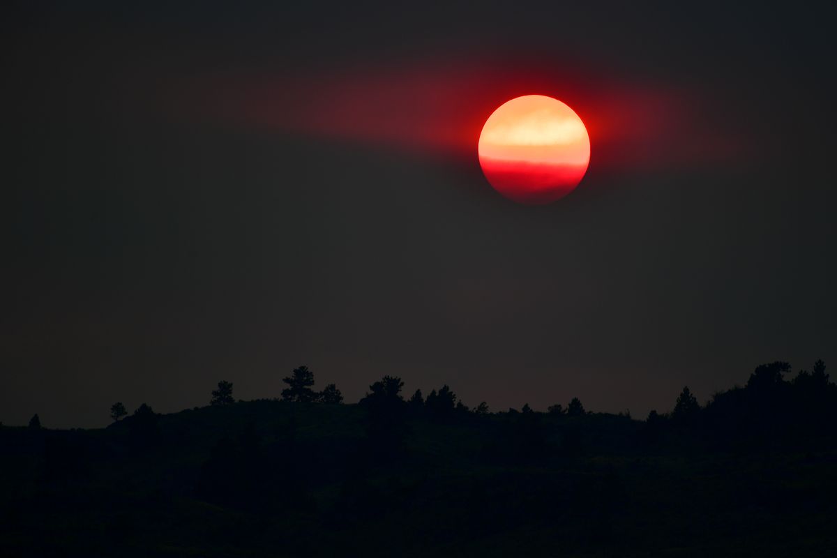 Smoke from several wildfires burning in north eastern Washington shrouds the sun and enhances its color as it sets on Saturday, July 17, 2021, near Omak, Wash.  (Tyler Tjomsland/The Spokesman-Review)