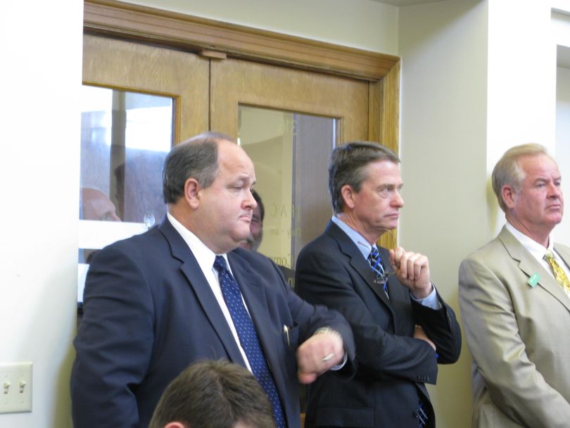 Senate Majority Leader Bart Davis, left, checks his watch as the Joint Finance-Appropriations Committee debates half an hour past the time the Senate was supposed to start its session on Friday. JFAC was setting its budget target for next year. Also shown are Lt. Gov. Brad Little, center, and lobbyist Skip Smyser, right. (Betsy Russell / The Spokesman-Review)