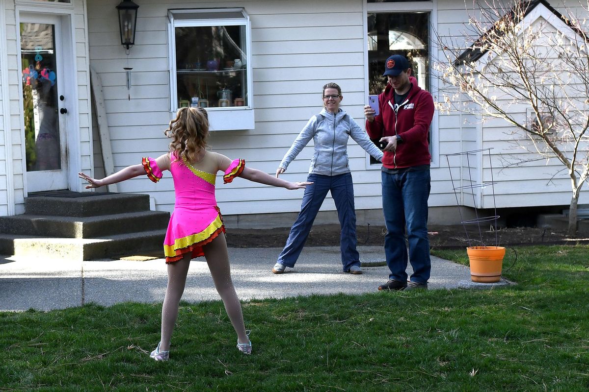 Moe Herr, center and her husband Alex Herr watch and film their daughter Morgan, 10, as she competes in the Lake City Figure Skating virtual competition from her home in Spokane on Saturday, April 4, 2020. (Kathy Plonka / The Spokesman-Review)