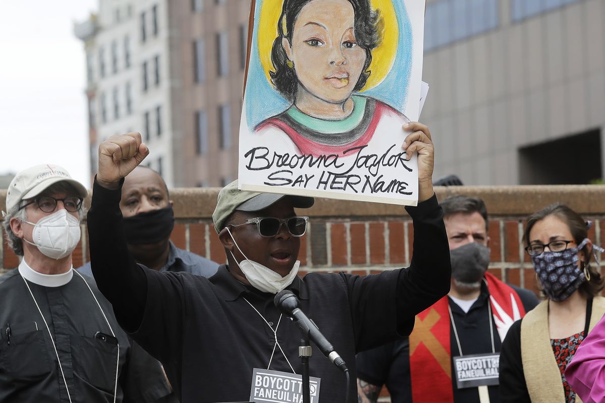 FILE - In this June 9, 2020, file photo, Kevin Peterson, center, founder and executive director of the New Democracy Coalition, displays a placard showing Breonna Taylor as he addresses a rally in Boston. Louisville