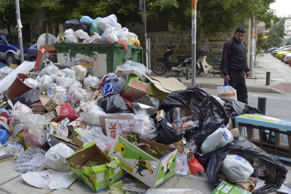 A pedestrian walks past a pile of garbage in the northern port city of Thessaloniki, Greece, on Sunday. Worker strikes have crippled garbage collection across Greece. (Associated Press)