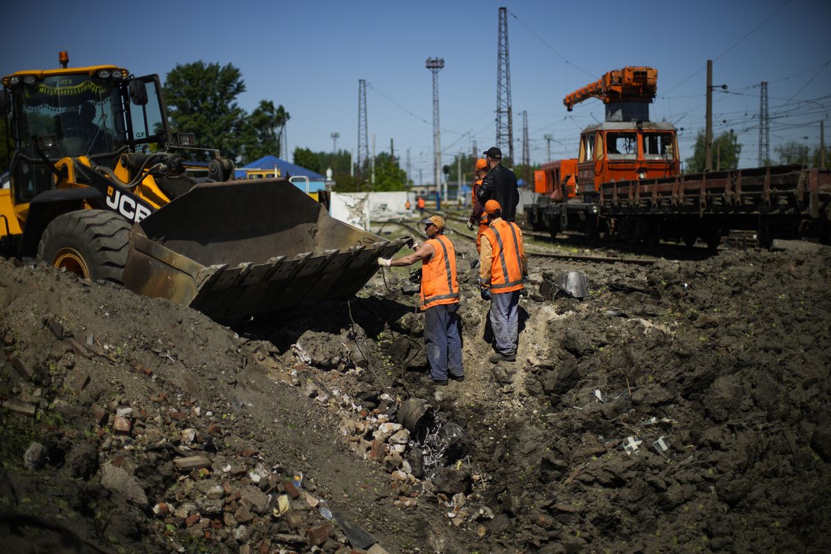 Workers remove pieces of a rocket from a crater after a Russian strike in Pokrovsk, eastern Ukraine, Wednesday, May 25, 2022. Two rockets struck the eastern Ukrainian town of Pokrovsk, in the Donetsk region early Wednesday morning, causing at least four injuries.  (Francisco Seco)
