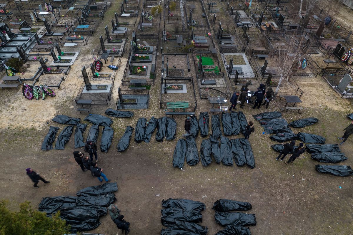 Policemen work on the identification process following the killing of civilians in Bucha, before sending the bodies to the morgue, on the outskirts of Kyiv, Ukraine, Wednesday, April 6, 2022.  (Rodrigo Abd)