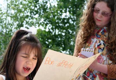 
Aidan Jones reads off a menu as Hannah Melton takes her order during a skit the children performed for their friends and family. 
 (Taryn Hecker / The Spokesman-Review)