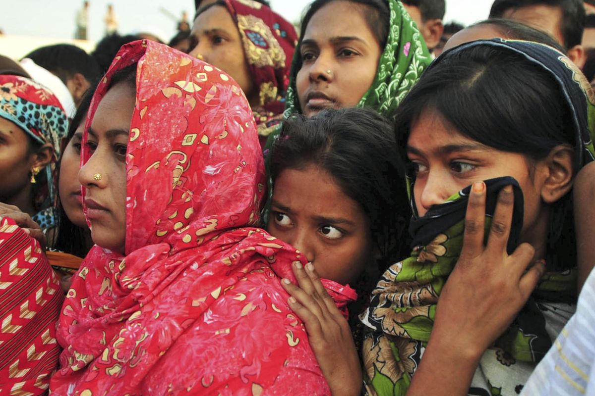 Bangladeshi women watch the bodies of some of the victims of Saturday’s fire in a garment factory being prepared to be buried in Dhaka, Bangladesh, on Tuesday. (Associated Press)