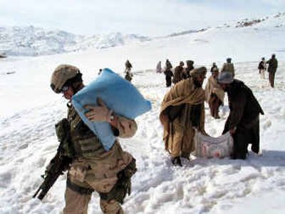 
A U.S. soldier carries food relief with local Afghans Monday for villagers hit by heavy snow in Zabul province of Afghanistan. 
 (Assoicated Press / The Spokesman-Review)
