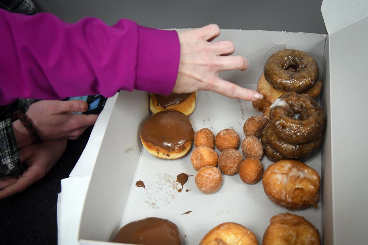 Laurie Krous points out the blueberry variety of donuts she had on a table during the reopening of the Donut Parade, Wednesday, March 13, 2019, in Spokane, Wash. (Dan Pelle / The Spokesman-Review)