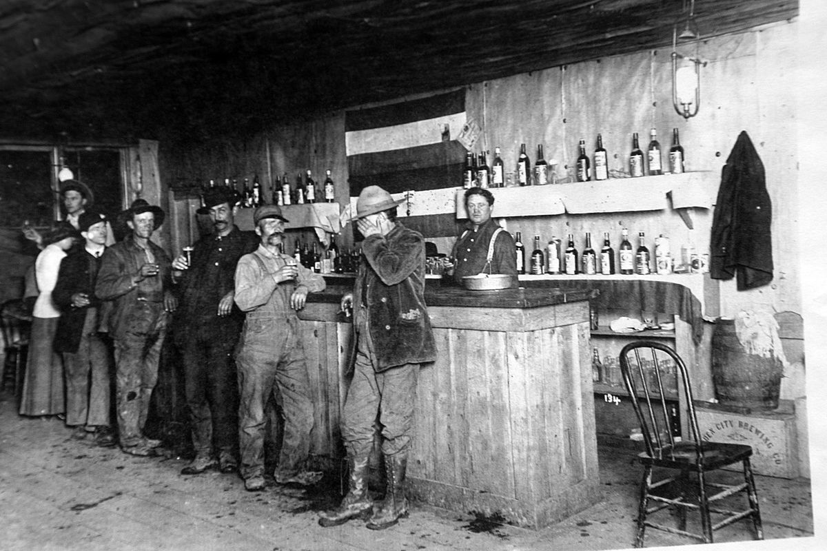  Patrons gather at a saloon in Grand Forks, circa the summer of 1908.  The patrons’ attire and flies on the wall indicate it’s summer, and the electric light on the ceiling indicates a time before a power plant at Taft was shut down in early 1909. 
 (Courtesy of U.S. Forest Service)