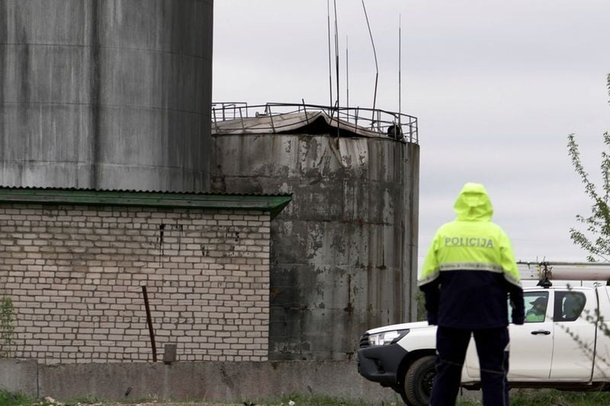 Police officer looks towards damage to an oil tank after drones crashed at a storage facility on Thursday, in Rezekne, Latvia.  (Reuters )