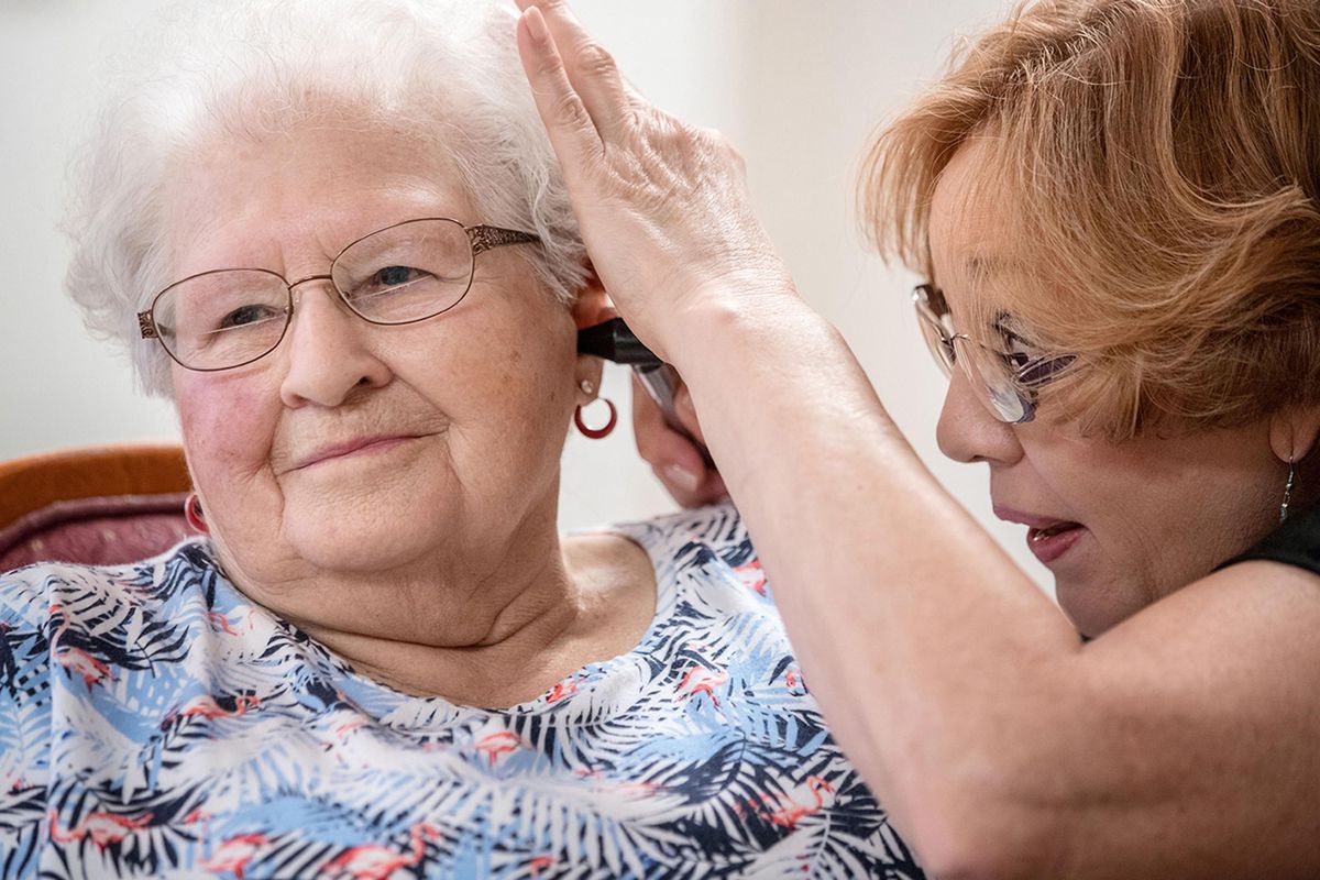Janie York examines the ear of Elaine Martin at the SilverRidge Assisted Living facility in Gretna, Neb., on Aug. 15, 2018. Martin had “quite a bit” of earwax before getting her ears cleaned by York and getting hearing aids, at her daughter’s urging. Now, York keeps Martin’s ears clear with regular cleanings. (CHRIS MACHIAN / Chris Machian/Tribune News Service)