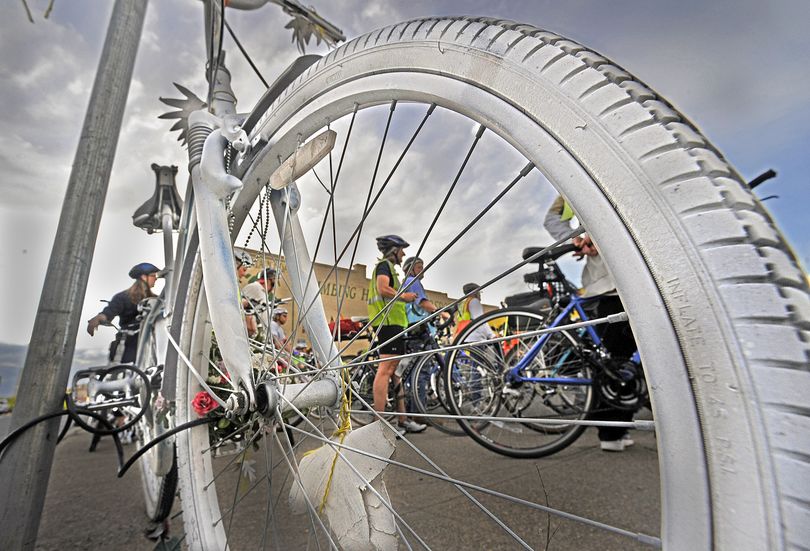 Bike riders participating in the Ride of Silence are framed in the white painted “ghost bike” at Sprague Avenue and Division Street on Wednesday. The white bike represents those riders injured or killed while riding. (Christopher Anderson)