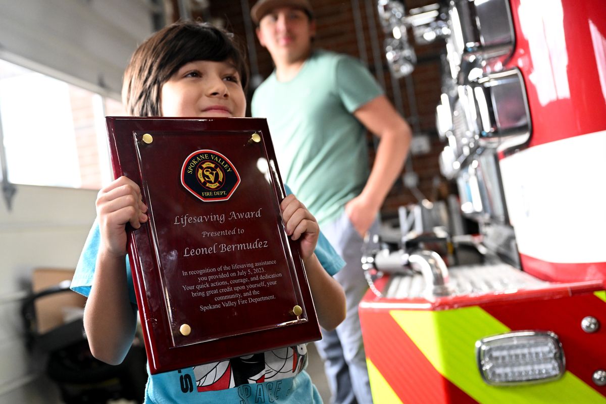 Leonel Burmudez, 8, poses for a photo with a Lifesaving award on Wednesday, Dec. 20, 2023, in Spokane Valley, Wash. Bermudez recieved the award for saving his mother’s life after she had a seizure and Bermudez called 911 and Captain Loftin and his crew responded. (Tyler Tjomsland/The Spokesman-Review)