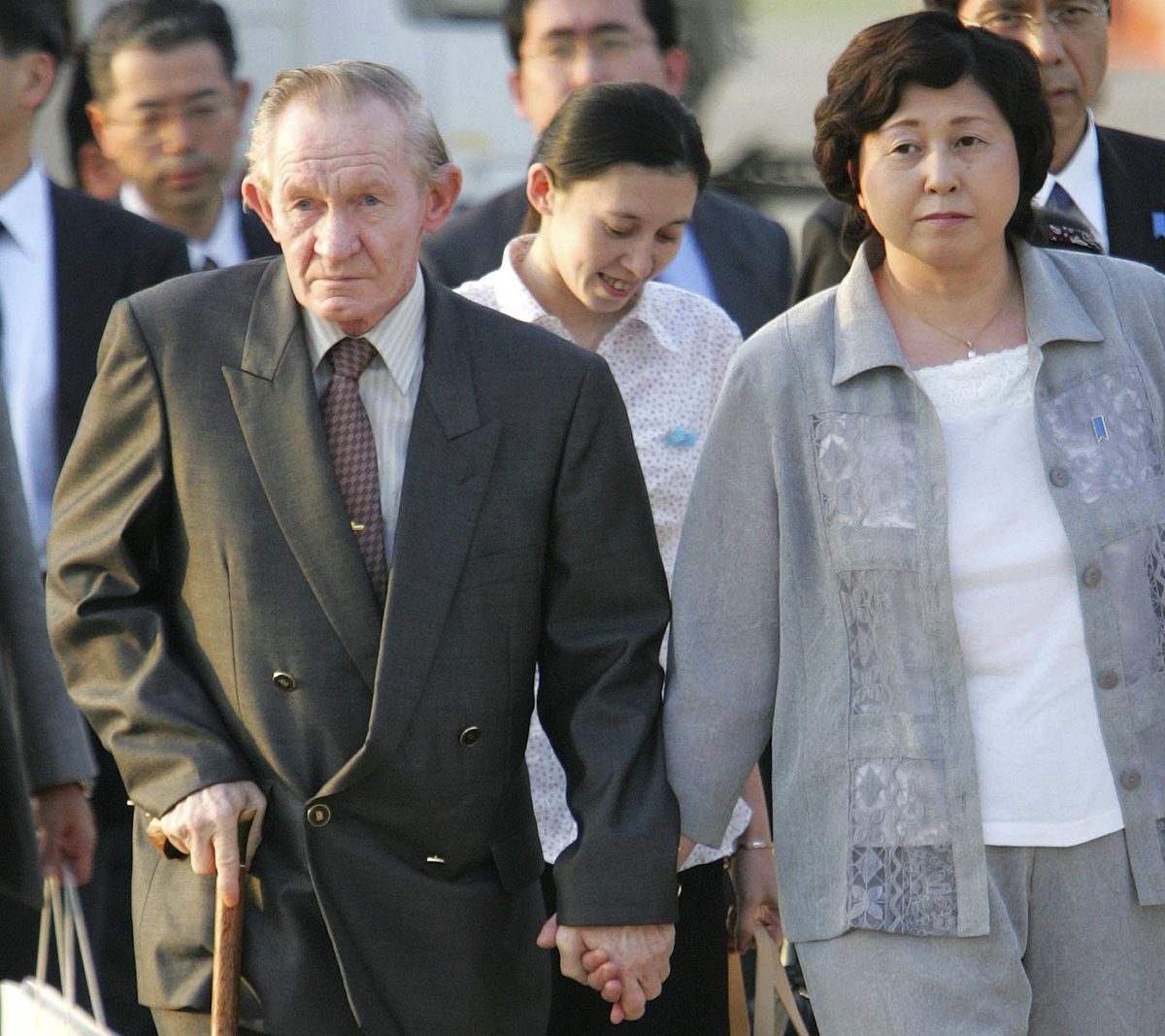 In this July 18, 2004  photo, former U.S. Army deserter to North Korea, Charles Jenkins, left, escorted by his wife, Hitomi Soga, right, and their daughter Mika, center, arrives at Tokyo’s Haneda International Airport. Jenkins, who married Soga, a Japanese abductee, and lived in Japan after their release in the 2000s, has died. He was 77. (Itsuo Inouye / AP)