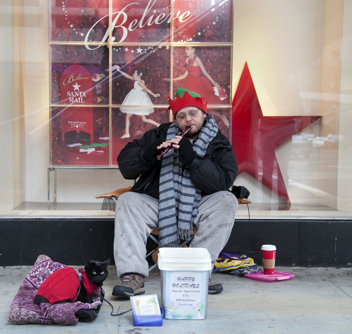 With his cat Muffen by his side, Talan Wilhelm plays Christmas music on his recorder Tuesday at Main Avenue and Howard Street. (Dan Pelle)