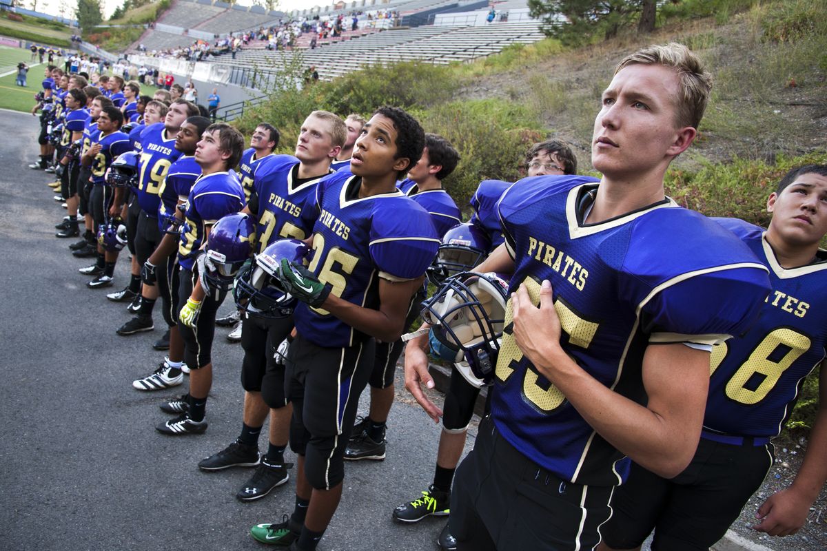Rogers High School football player Mads Tranberg, right, and his teammates honor the United States during the playing of the national anthem before the homecoming game against North Central in September. Rogers lost 28-21 and fell to 0-3 for the season. (Dan Pelle)