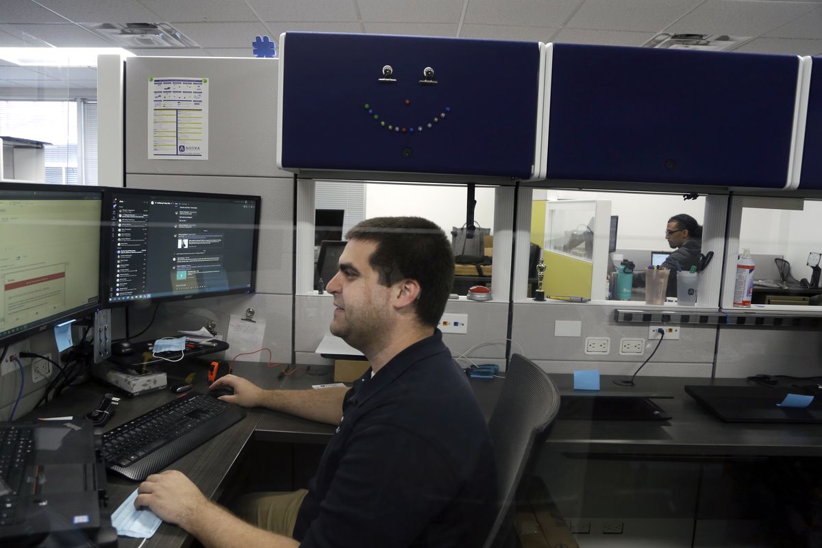 IT Support Specialist Joe Coladonato, left, and Tech Support Specialist Jaquan Robinson, right, work at Agora Cyber Charter School, Wednesday, Aug. 4, 2021, in King of Prussia, Pa. At Agora, officials said they have no plans to use the full $38 million the school was awarded and are exploring whether it’s possible to return unused money.  (Jacqueline Larma)